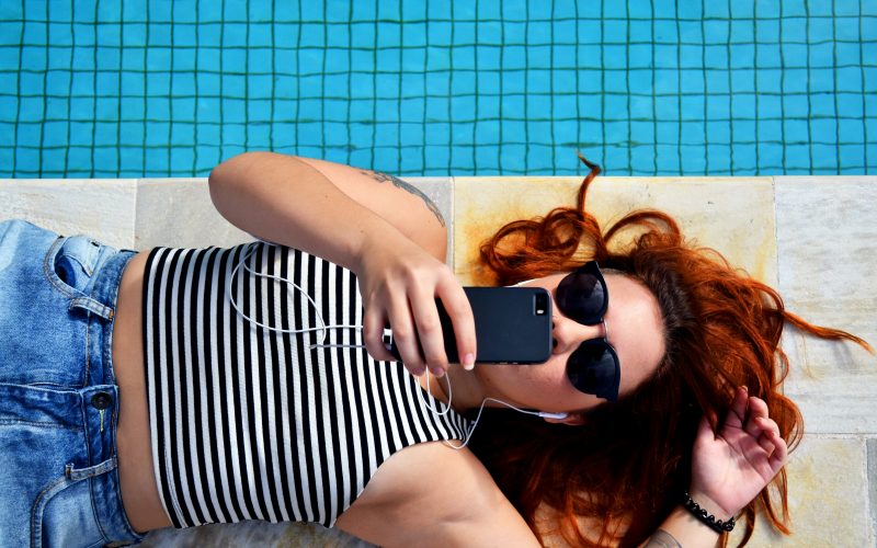 woman laying down by pool looking at phone