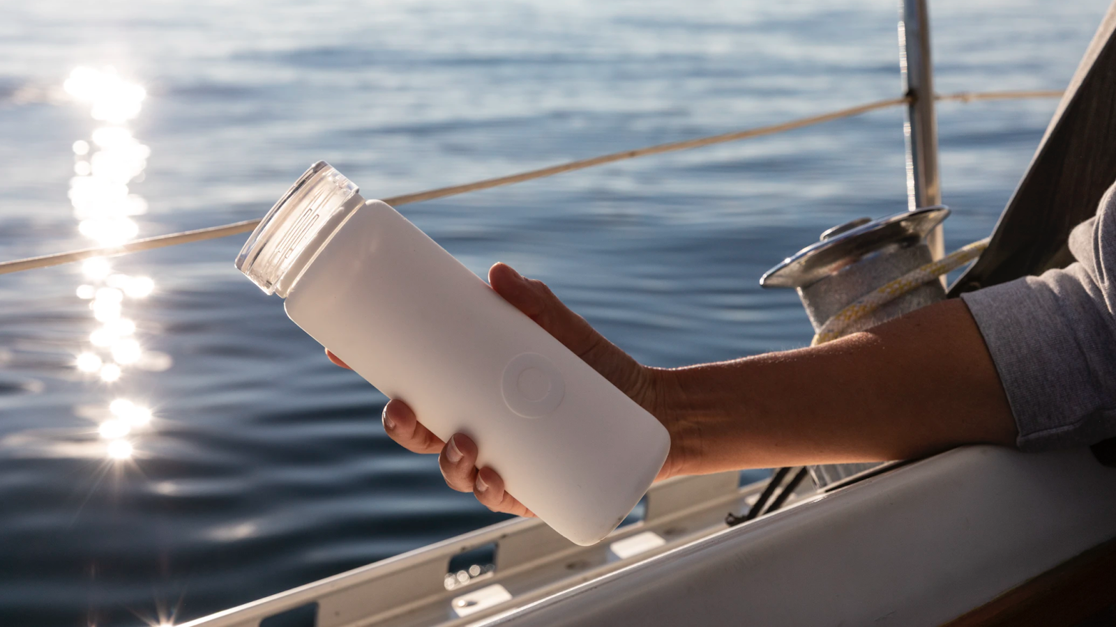 person holding reusable water bottle on a boat