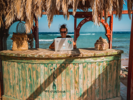 digital nomad working on laptop on beach